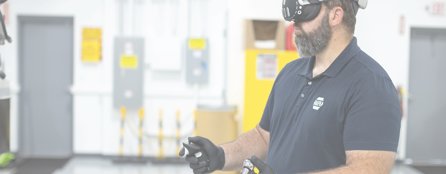 Automotive technician wearing a virtual reality headset and holding controllers during immersive training in an automotive workshop.