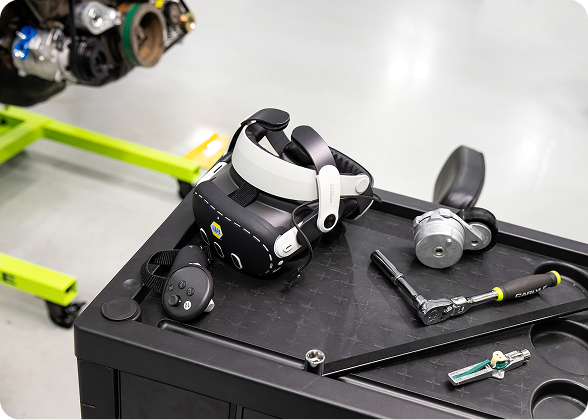 Virtual reality headset, controller, and automotive tools displayed on a service cart in an automotive training workshop.