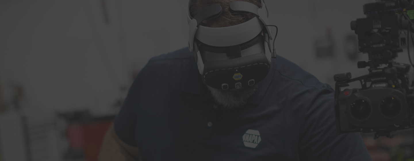 Automotive technician wearing a virtual reality headset during immersive training in an automotive workshop.