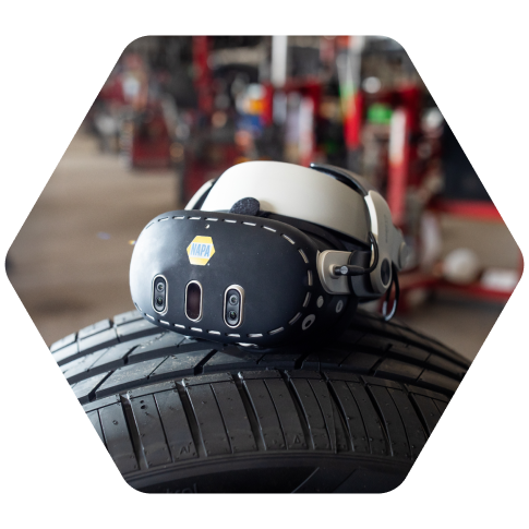 Virtual reality headset resting on a vehicle tire in an automotive workshop.