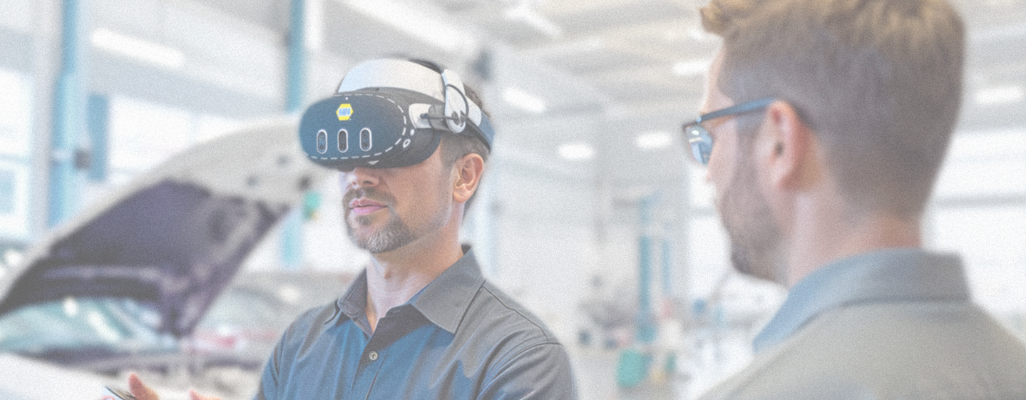 Automotive technician wearing XR Training Goggles while another technician observes during training in an automotive workshop.